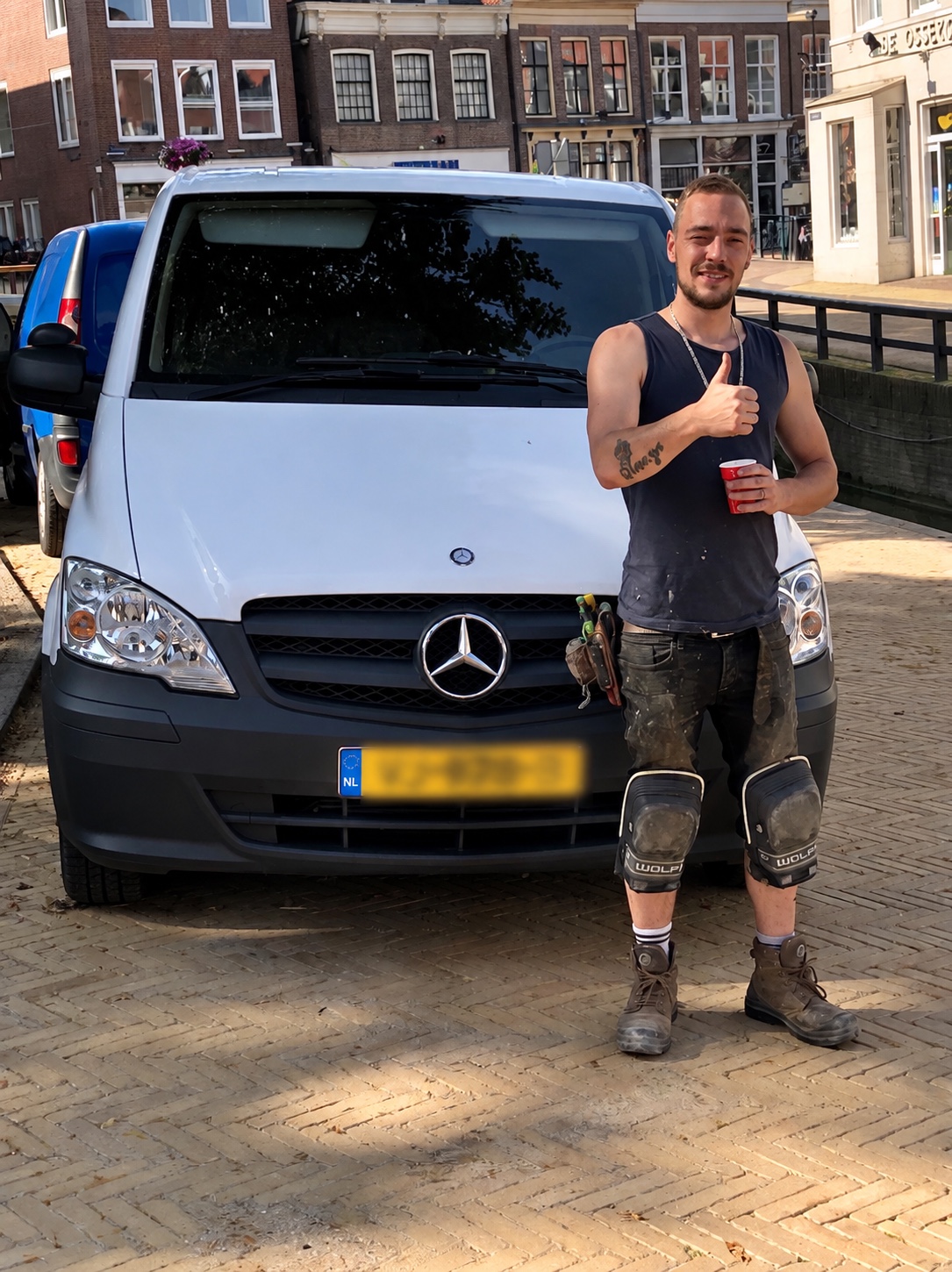 Mertens in werkkleding voor zijn bedrijfsbus met het kenteken onleesbaar gemaakt